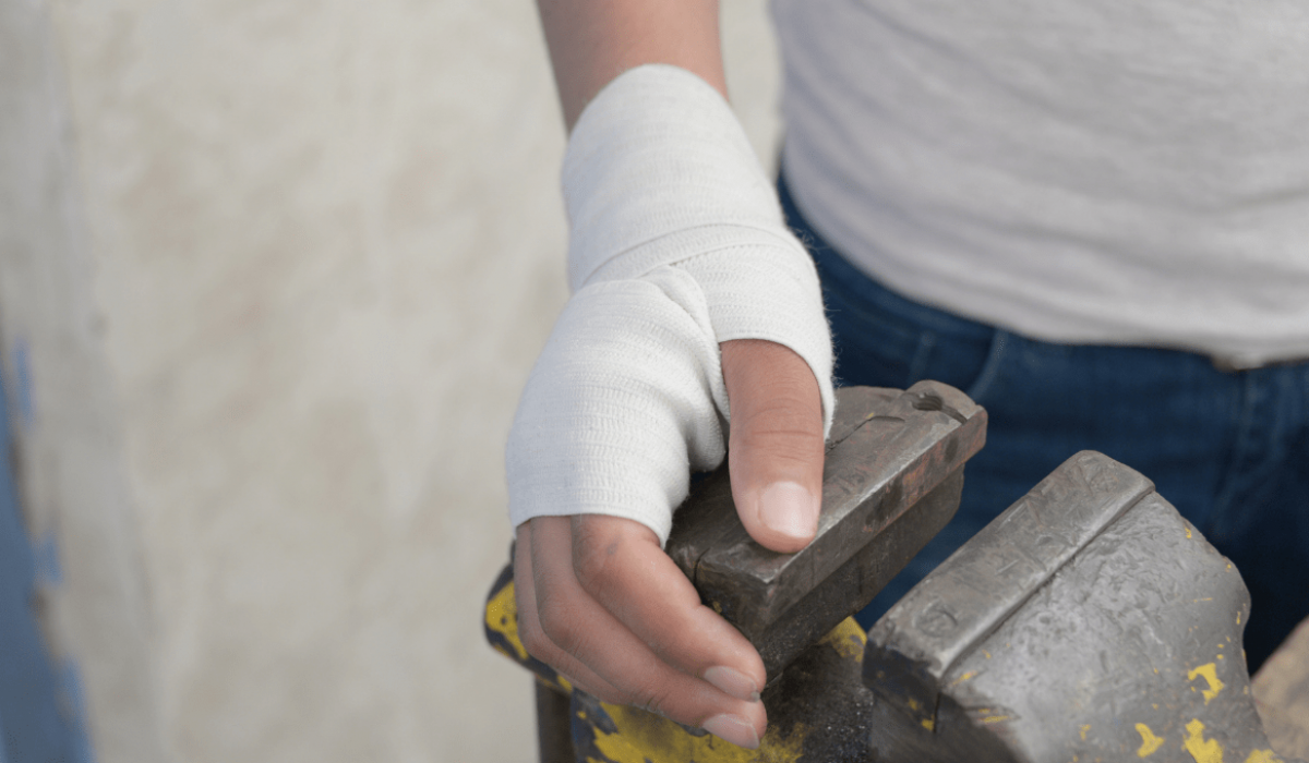 Un trabajador coloca su mano vendada sobre un tornillo de banco.