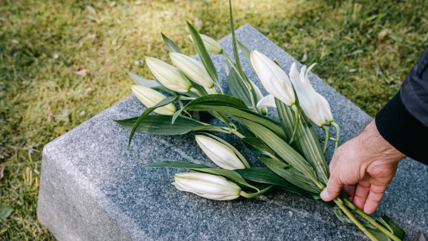 Persona dejando flores en una lápida